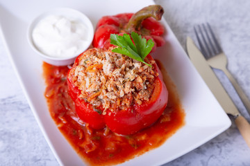 Peppers stuffed with meat, rice and vegetables with tomato sauce and sour cream. A traditional dish. Close-up.