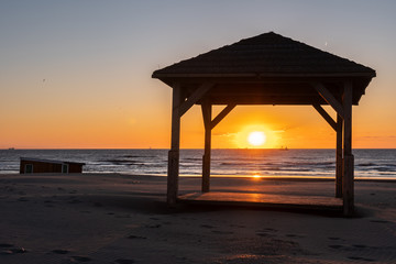 Silhouete of gazebo on the sea beach in beautiful sunset with serene sea in the background
