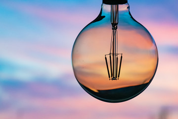 Sunset in a light bulb. Electricity concept. Earth hour. Energy consumption and environmental...