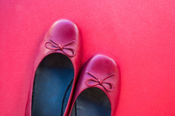Stylish female flat shoes in dark red color on dark red background. Beauty and fashion concept.