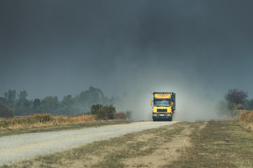 big truck going fast dirt road, a large cloud of dust