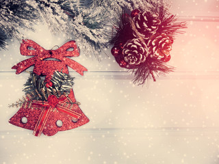christmas bell on fir tree branch with cones and snow on background