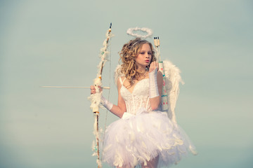 Charming curly little girl in white dress and wings - angel cupid girl. Portrait of little curly...
