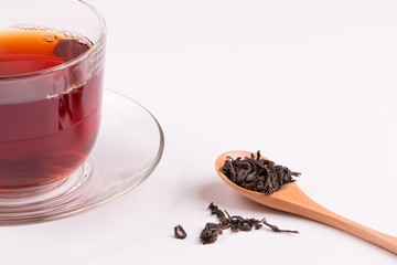 Cup with tea close up. Loose tea in a wooden spoon and a cup of freshly poured black tea.