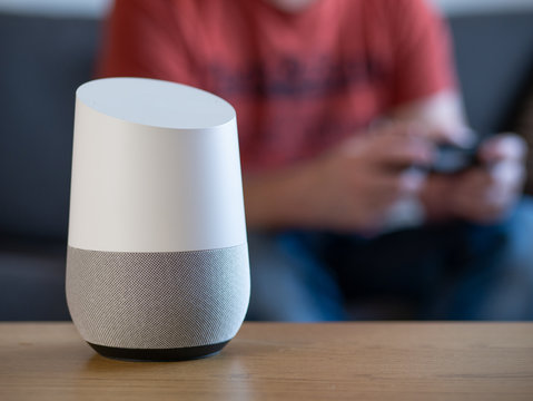 smart home voice activated speaker in lounge with gamer in background