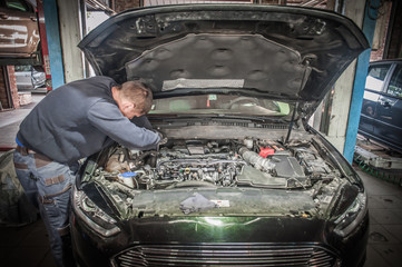 Car mechanic repairer service technician checks and repairs auto engine