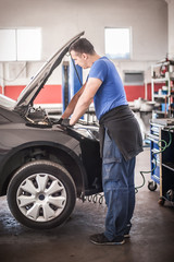 Obraz na płótnie Canvas Car mechanic repairer service technician checks and repairs auto engine