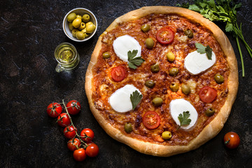 pizza with mozzarella and tomato sauce, herbs and olives on a dark background