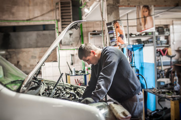 Fototapeta na wymiar Car mechanic repairer service technician checks and repairs auto engine