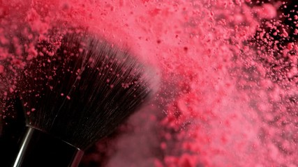 Super slow motion of makeup brush with falling pink powder, black background. Filmed on high speed cinema camera, 1000fps.