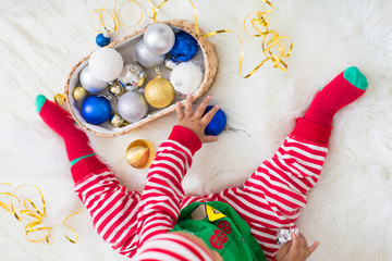 Baby elf playing with colorful Xmas balls