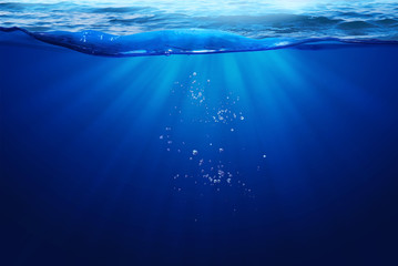 Deep Blue Sea Under Water Light Ray Through on Wavy Sea Surface  And Small Bubbles Under The Ocean...