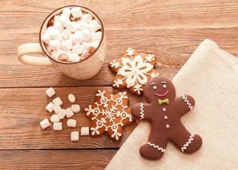 A beige Cup of traditional Christmas hot chocolate or cocoa with marshmallow. Christmas gingerbread on wooden background