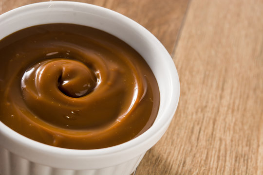 Traditional Latin American dulce de leche or manjar on wooden background.. Copy space