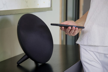 Woman using her smartphone to connect it with speaker via bluetooth