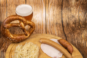 fête de la bière (oktober fest) avec un verre de bière un bretzel géant et une choucroute garnie sur assiette en bois - fond bois clair espace pour texte ressource graphique