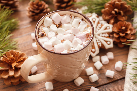 A beige Cup of traditional Christmas hot chocolate or cocoa with marshmallow. Christmas gingerbread on wooden background