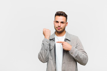 young hispanic man looking impatient and angry, pointing at watch, asking for punctuality, wants to...