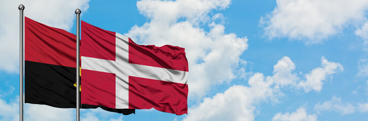 Angola and Denmark flag waving in the wind against white cloudy blue sky together. Diplomacy concept, international relations.
