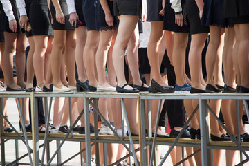 Legs of girls stand in a row
