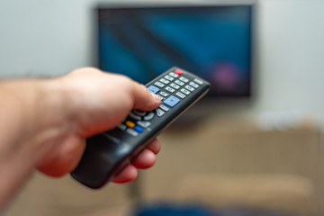 A person with a TV remote controls the remote control to switch channels to watch TV shows.