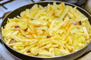 Sliced fried potatoes in a pan in the home kitchen.