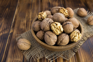 Walnuts in the brown bowl on the rustic  wooden  background. Closeup.