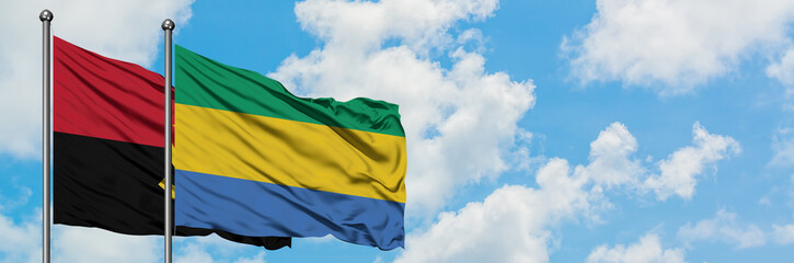 Angola and Gabon flag waving in the wind against white cloudy blue sky together. Diplomacy concept, international relations.