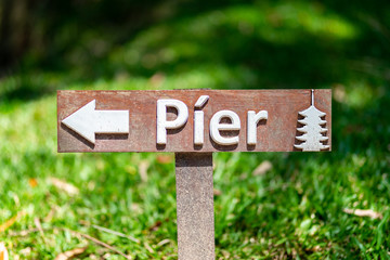 Placa de madeira sinalizando a direção do píer próxima ao templo japonês. Escrito em português