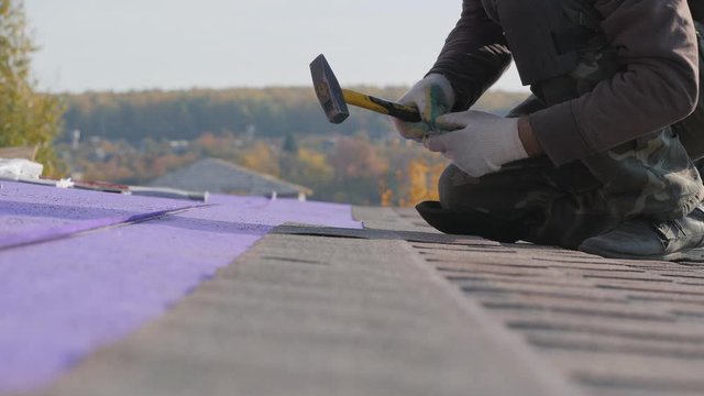 Laying a soft roof. Work at height. Fastening of a sheet of material by means of nails and a hammer.