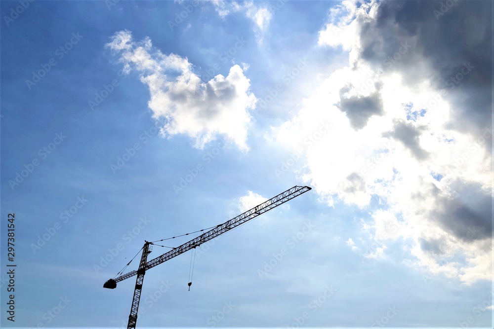 Wall mural construction crane tower against a blue sky, clouds