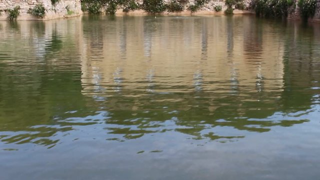 Beautiful view of the house reflected on the water in the Bagno Vignoni thermal bath, Tuscany, Italy. HD video outdoors during the day. Concept of relaxation, tranquility and peace.