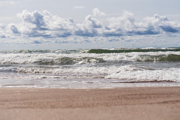 Beautiful view of wavy sea on a sunny day with dramatic clouds. Vacation and holidays background, global warming and climate change concept