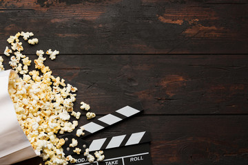 Cinema concept. Popcorn in a box and movie clapper on wooden background top view. Free space.