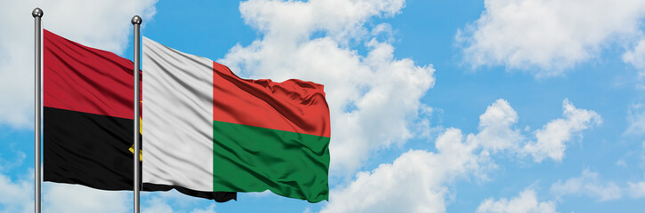 Angola and Madagascar flag waving in the wind against white cloudy blue sky together. Diplomacy concept, international relations.