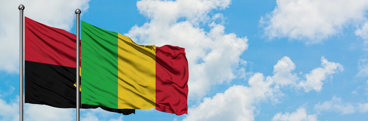 Obraz premium Angola and Mali flag waving in the wind against white cloudy blue sky together. Diplomacy concept, international relations.