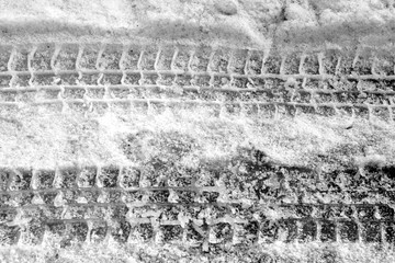 Car tyre prints in snow in black and white.