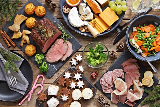 Christmas dinner table with roast beef, appetizers platter and traditional cookies. Christmass celebration, festive family dinner.  Overhead view.