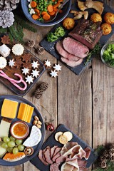 Christmas dinner table with roast beef, appetizers platter and traditional cookies. Christmass celebration, festive family dinner.  Overhead view.