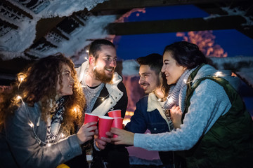 Group of young friends outdoors in snow in winter at night, holding sparklers.