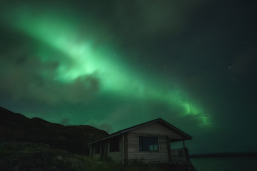 Northern Lights, Aurora Borealis in Kola Peninsula at night sky illuminated green. Murmansk region, Russia