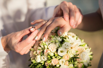 Obraz na płótnie Canvas Hands of the bride and groom on a wedding bouquet. Wedding day.