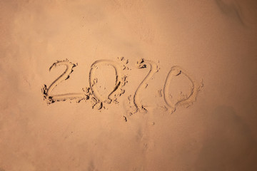 Inscription with a finger on the sand. Figures happy new year 2020.