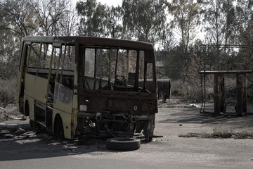 Burnt bus in an abandoned park. Card in the style of post-apocalypse.
