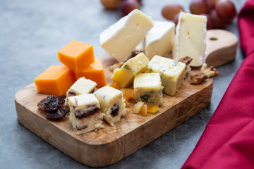 Various different types of cheese slices, cheese mix on wooden cutting board. Wine snack. Camembert, parmesan, brie cheese.