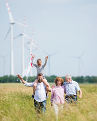 Multigeneration family walking on field on wind farm.