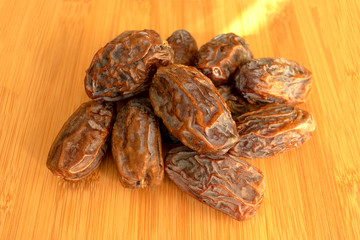 Fresh arabic dates isolated on light wooden table. Date palm fruit. Pile of dates.