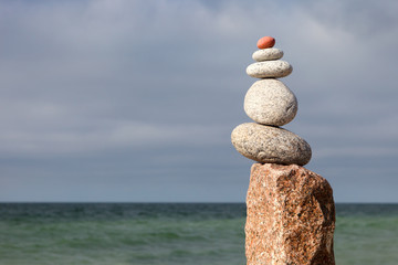 Fototapeta na wymiar Rock zen pyramid of white pebbles on the background of the sea. Concept of balance, harmony and meditation.