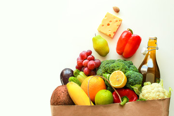 Full paper bag of healthy food on a white background. A basket full of fresh vegetables and fruits. A concept of proper nutrition delivery. Vegetarian food in a craft bag. With space for copywriting.