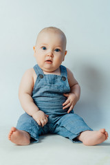 Little surprised boy sits on a white background and looks at the camera